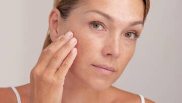 Kobieta z piegami na twarzy dotykająca skóry