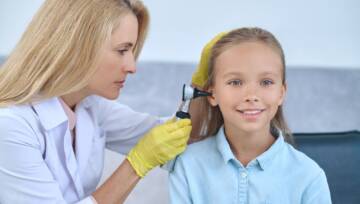 Lekarz bada ucho młodych dziewcząt za pomocą urządzenia medycznego