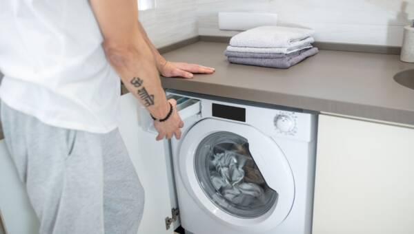 Zbliżenie na dłonie mężczyzny otwierające pralkę