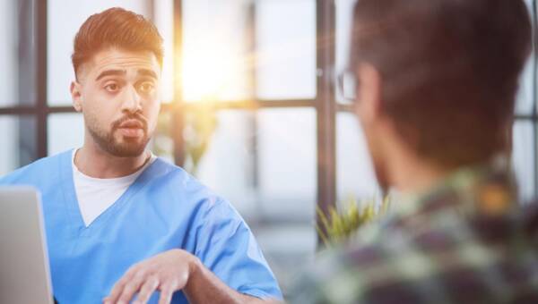 mężczyzna mówi coś do lekarza w tajemnicy