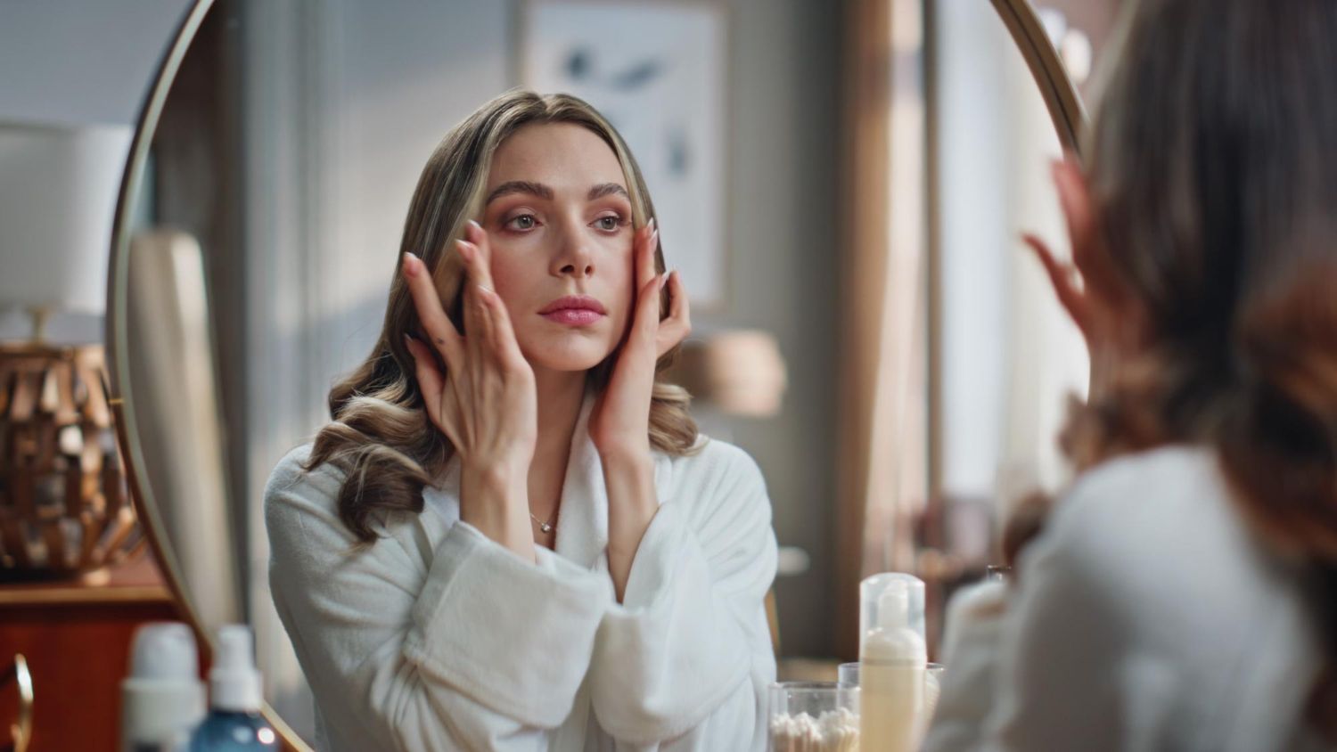 Piękna dama dotykająca skóry patrząca w lustro 