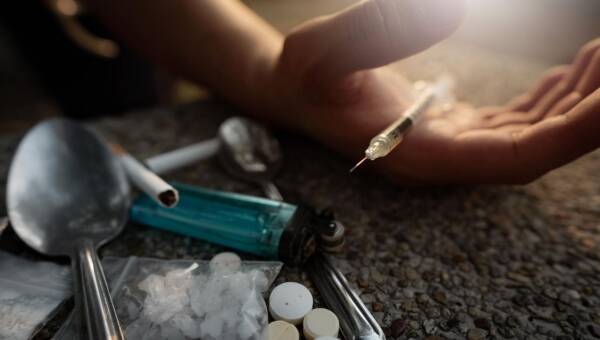 ręka osoby trzymającej strzykawkę na podłodze