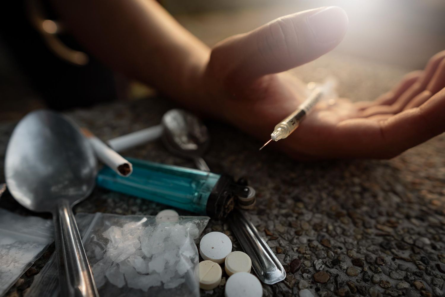 ręka osoby trzymającej strzykawkę na podłodze