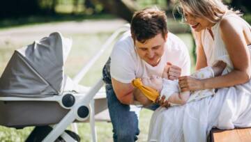 Młoda para z córką siedząca przy wózku dla niemowląt