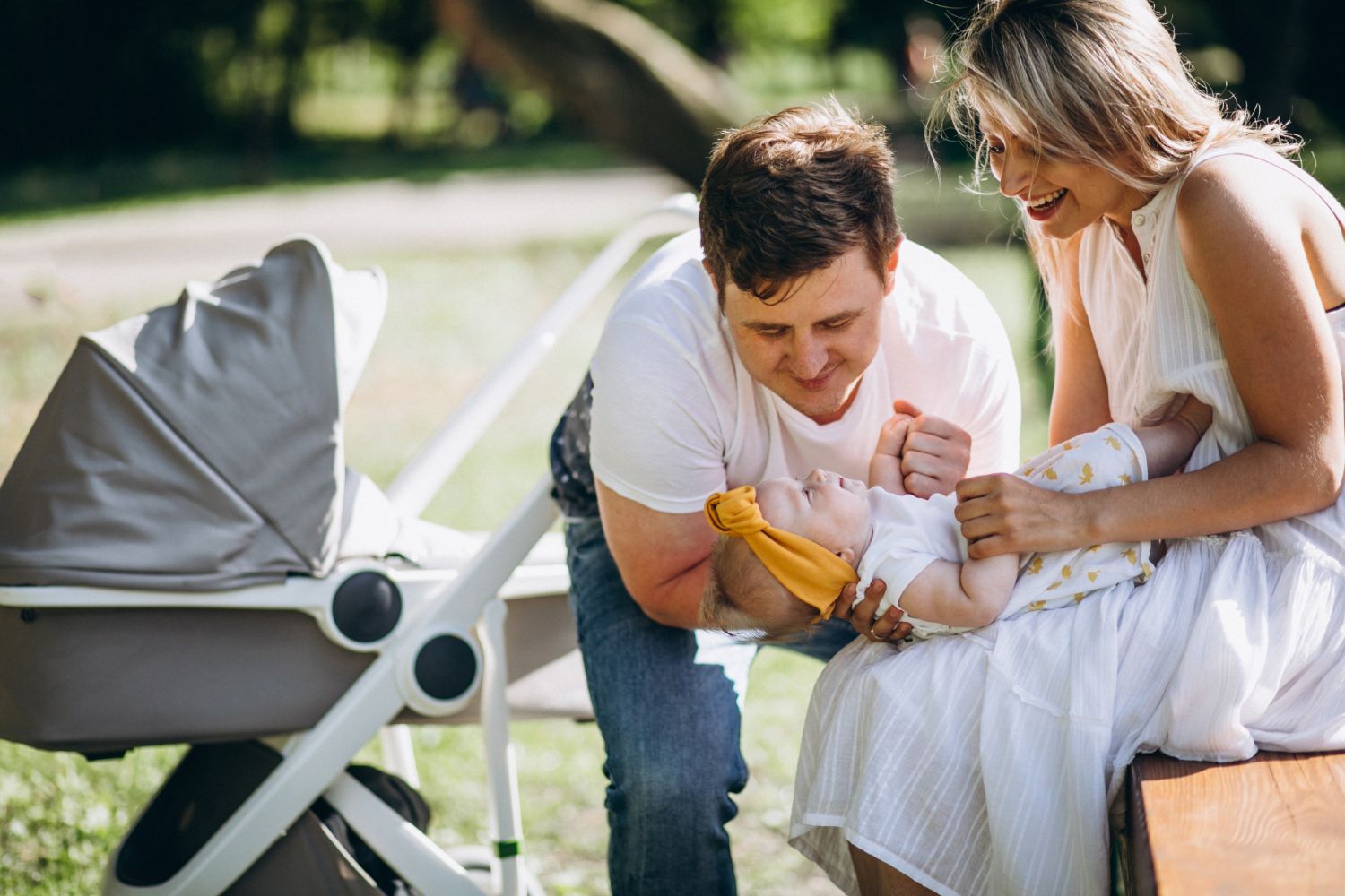 Młoda para z córką  siedząca przy wózku dla niemowląt