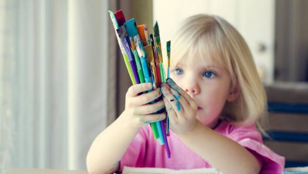 Portret małej dziewczynki z pędzlami w domu