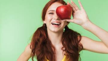 kobieta z jabłkiem i ładnymi zębami