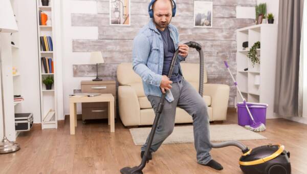 mężczyzna odkurza w domu