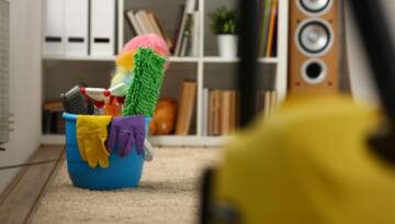 Wiadro z sprzętem do czyszczenia stoi na dywanie w pokoju