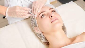 Kosmetolog wykonuje zastrzyk odmładzający w twarzy kobiety