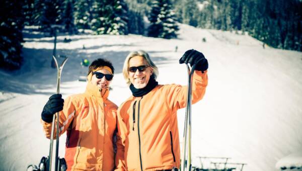 Portret pary trzymającej narty, stojącej na śniegu