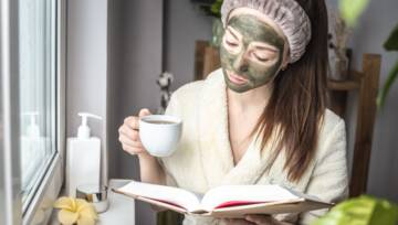 Kobieta w szlafroku z zieloną kosmetyczną maską na twarzy wykonaną z herbaty