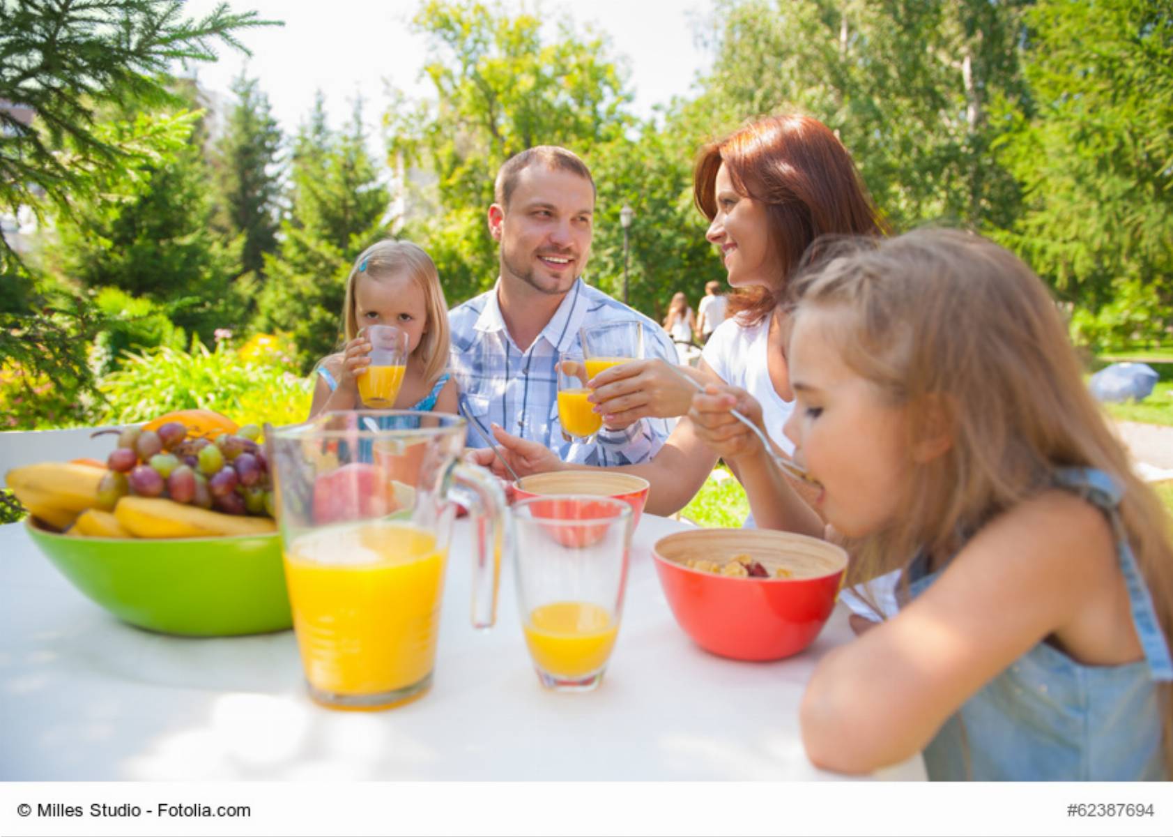 Family eating together outdoors at summer park or backyard