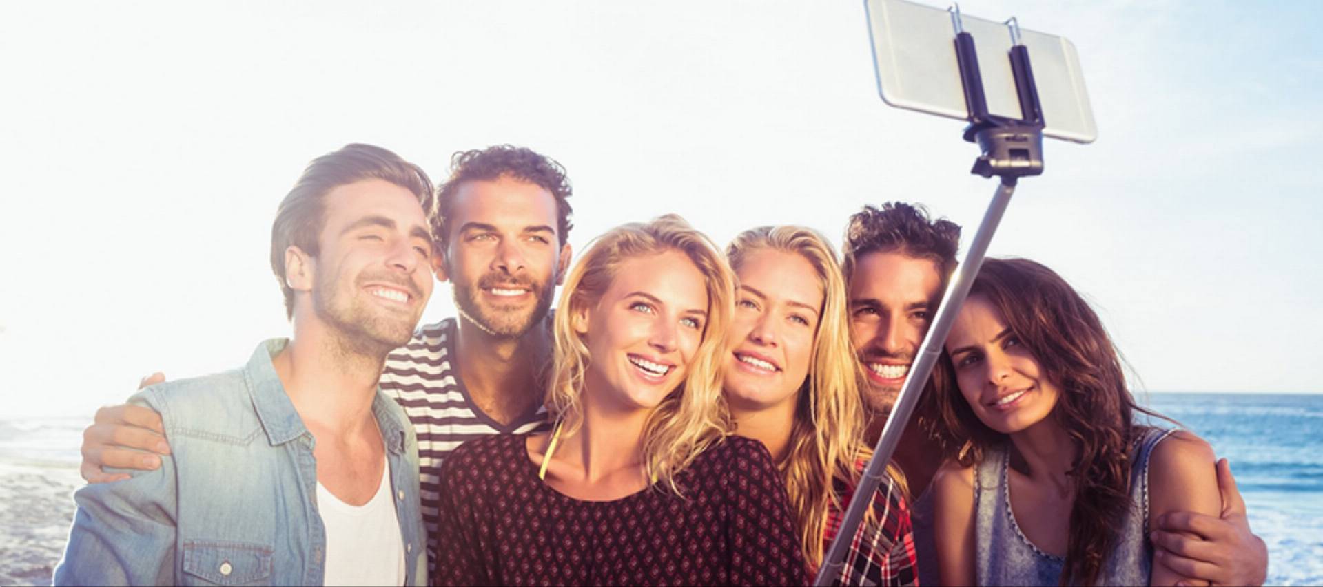 Happy friends taking selfie with selfie stick