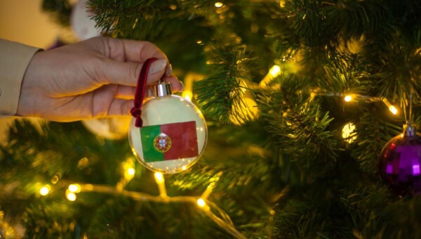 Dziewczynka trzyma dekorację na choince z flagą portugalii