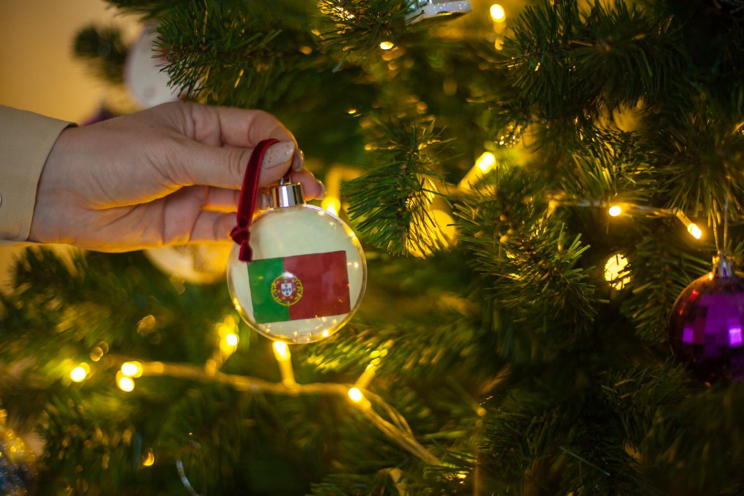 Dziewczynka trzyma dekorację na choince z flagą portugalii