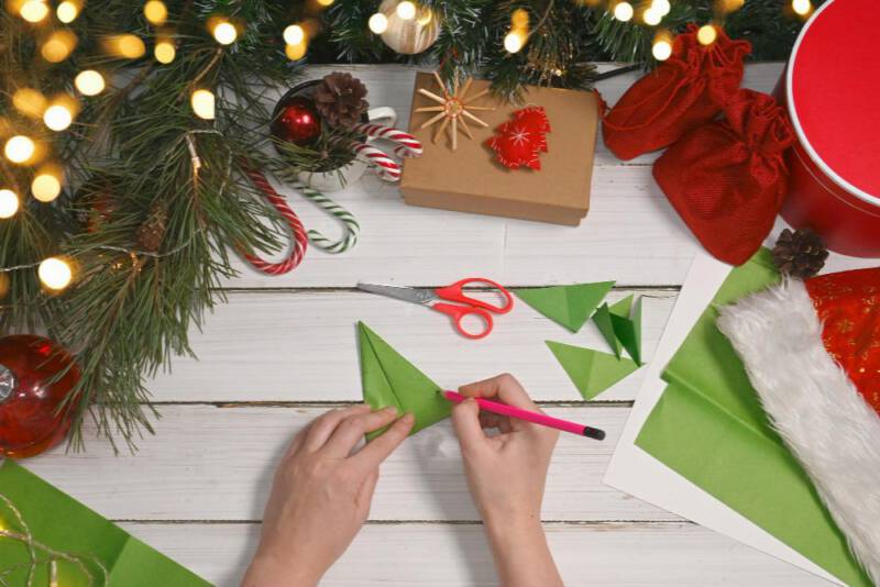 na powstałym, złożonym trójkącie narysuj linie jak na zdjęciu, aby wyciąć trójkąty, które staną się gałązkami papierowej choinki.