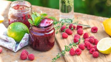 Dżem malinowy i świeże maliny na rustykalnym drewnianym stole w ogrodzie