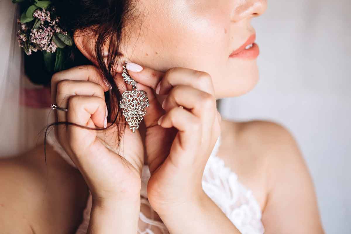 kobieta zakłada ażurowy kolczyk