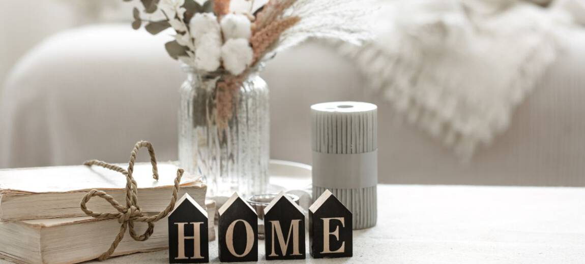 Przytulny salon ze świecami zapachowymi, bukietem suszonych kwiatów i napisem home