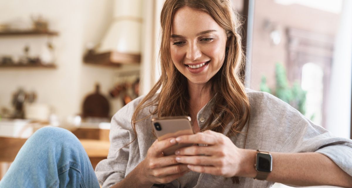 kobieta patrzy na telefon z uśmiechem Freepik kobieta patrzy na telefon z uśmiechem