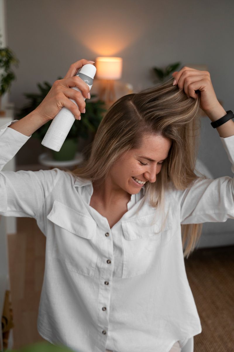 kobieta używa sprayu do włosów