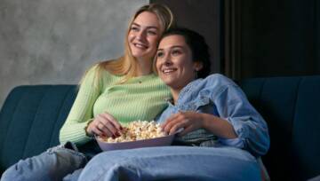 dwie kobiety oglądające film z popcornem