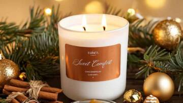 Świeca Sweet Comfort Luméa Candle z woskiem sojowym, otoczona cynamonem, karmelem i piernikiem w świątecznej aranżacji. Ciepłe światło i złote dekoracje.