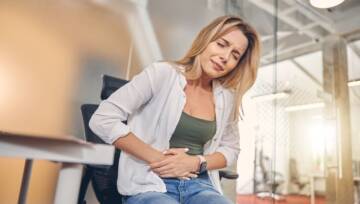 kobieta trzymająca się za bolący brzuch