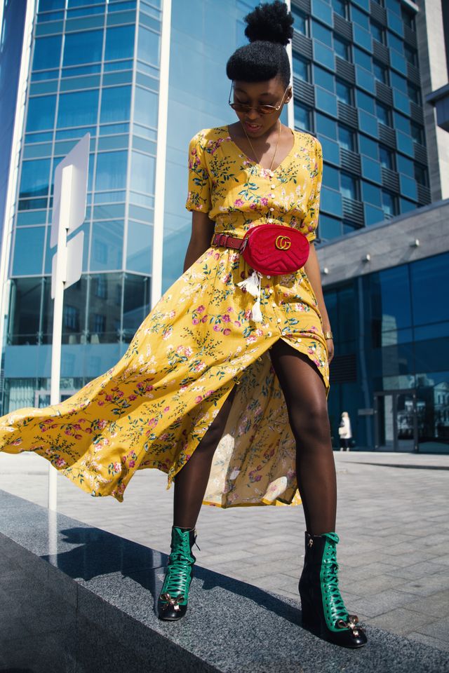 zerwona welurowa nerka Gucci GG Marmont ze złotym logo noszona w pasie do żółtej sukienki w kwiaty w stylizacji street style